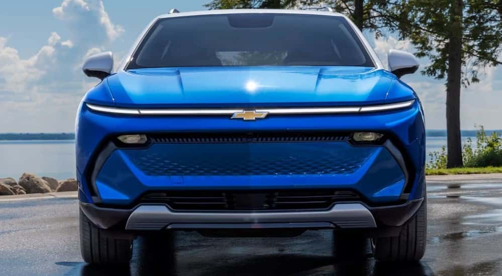 A blue 2025 Chevy Equinox EV for sale parked near water.
