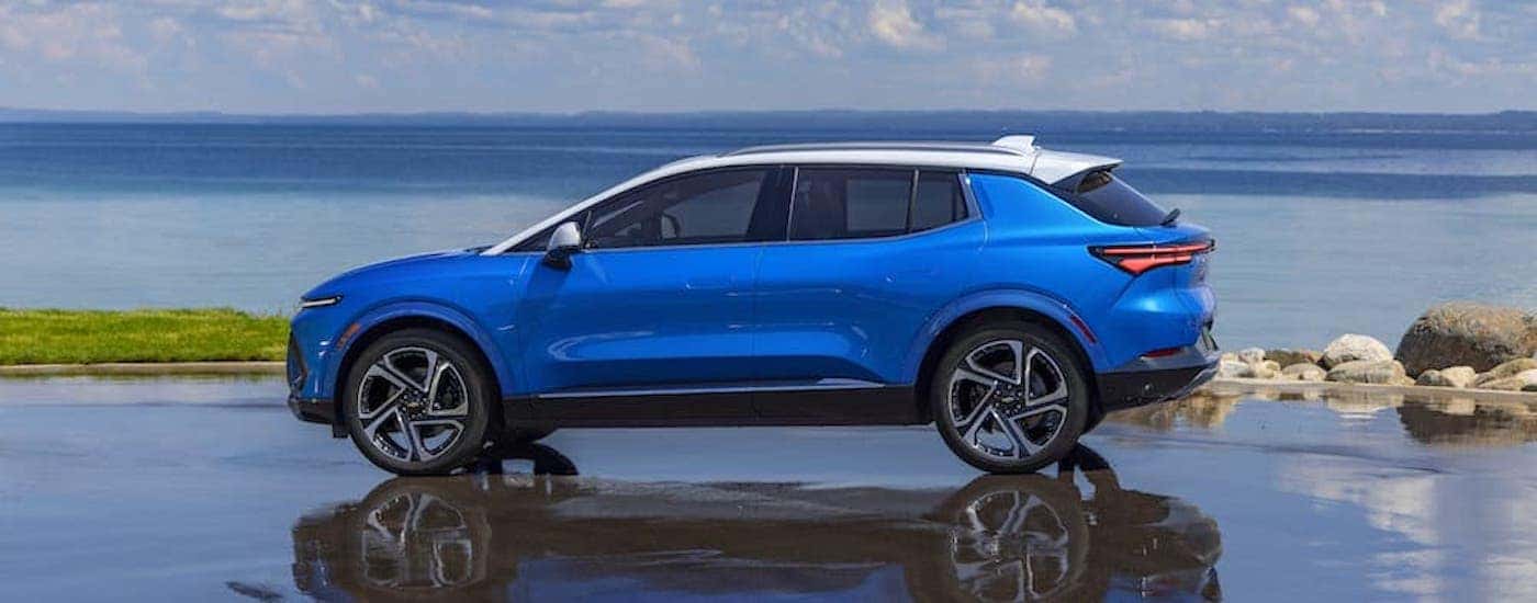 A blue 2024 Chevy Equinox EV parked near an ocean.