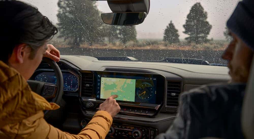 Two people sitting in the front seats in the grey interior of a 2025 Chevy Silverado 1500.
