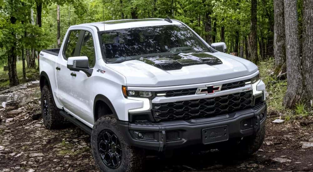 A white 2025 Chevy Silverado 2500 ZR2 driving through a forest.