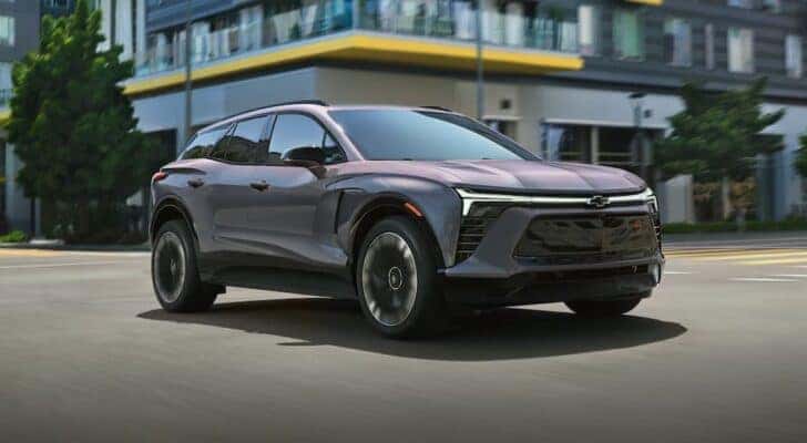 A gray 2025 Chevy Blazer EV RS is shown driving on a city street.