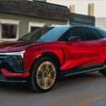A red 2025 Chevy Blazer EV RS is shown driving on a city street.