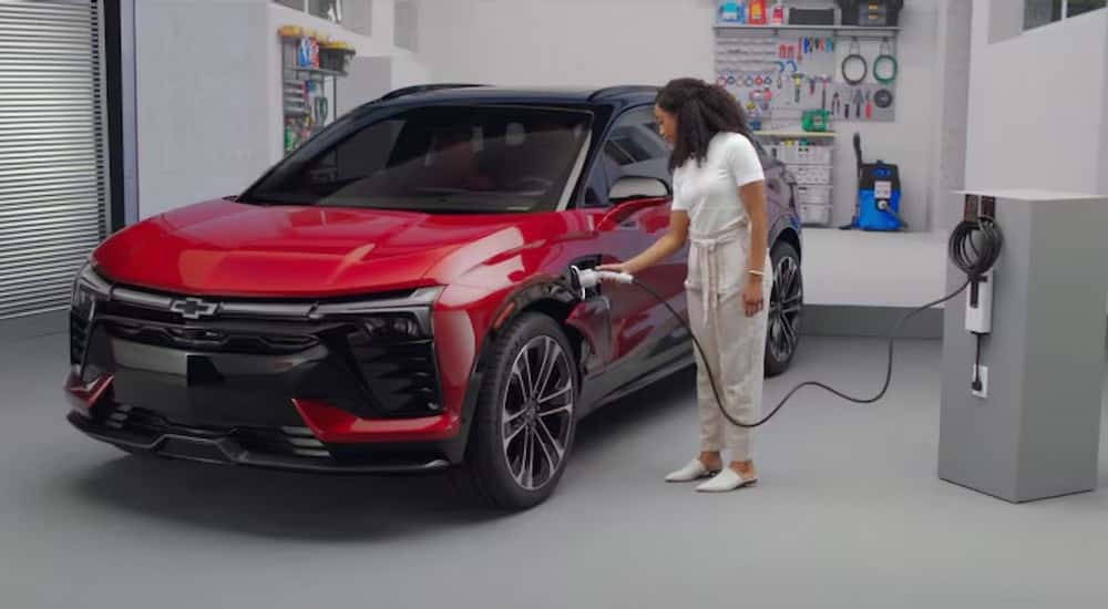 A red 2025 Chevy Blazer EV RS is shown charging in a garage.