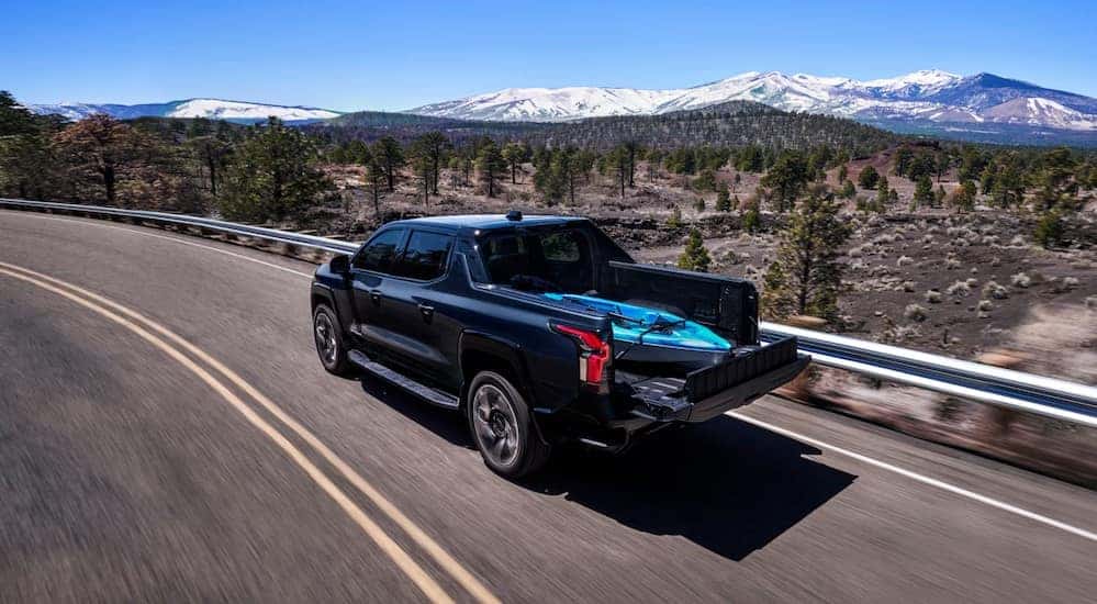A black 2025 Chevy Silverado EV RST is shown driving on a highway.