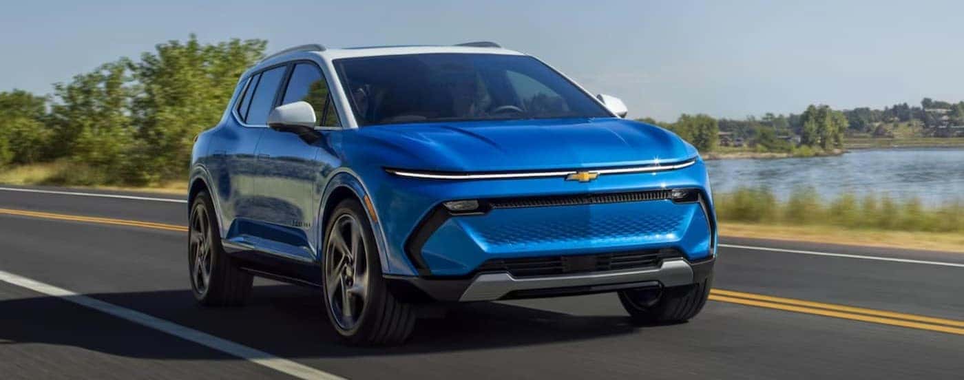 A blue 2024 Chevy Equinox EV is shown driving on a highway.