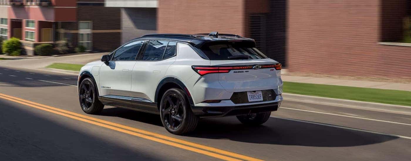 A white 2025 Chevy Equinox EV RS is shown driving to view a Chevy Equinox EV for sale near Mount Holly.