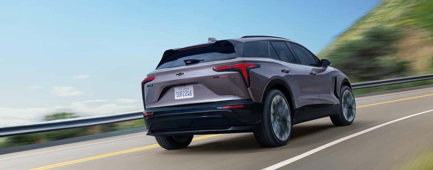 Rear view of a grey 2025 Chevy Blazer EV RS driving down a road.