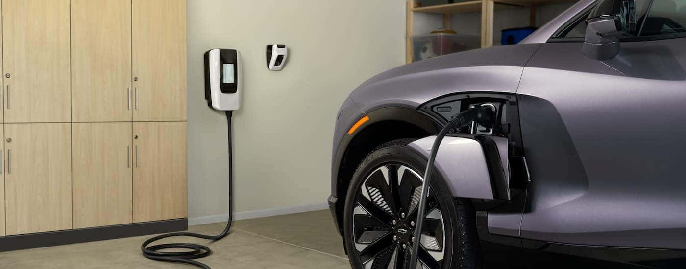 A grey 2025 Chevy Blazer EV parked in a garage and plugged into a wall charger.