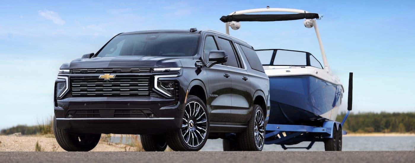 A black 2025 Chevy Suburban High Country towing a boat from a Chevy dealer near Kannapolis.