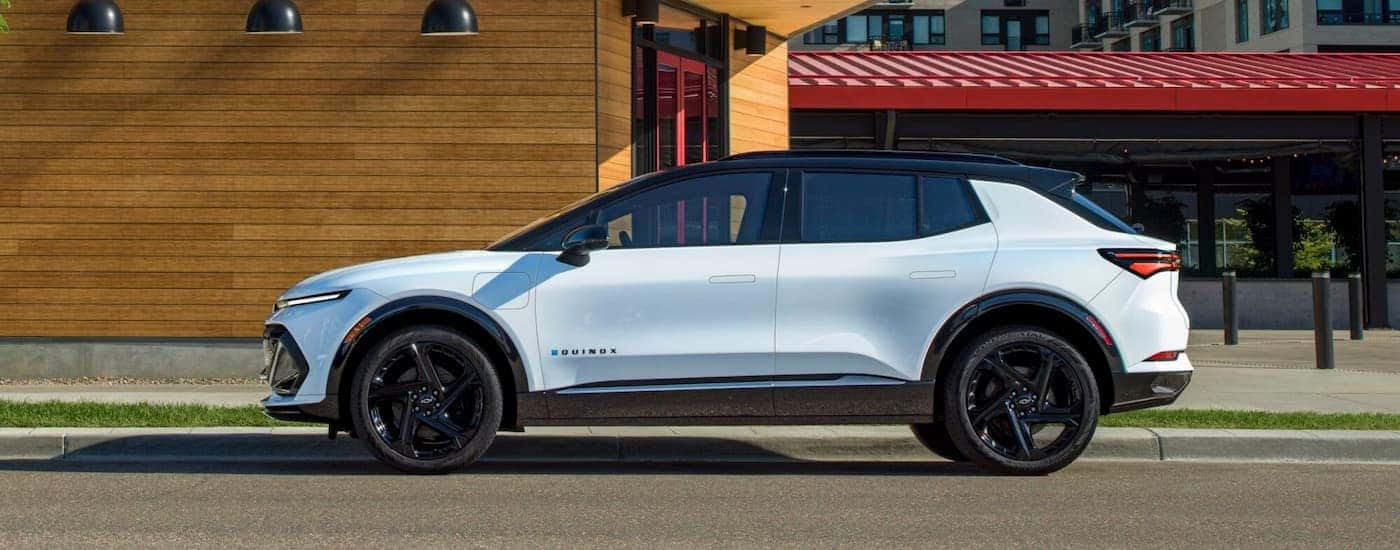 A white 2025 Chevy Equinox EV RS for sale in Charlotte parked on the side of a city street.
