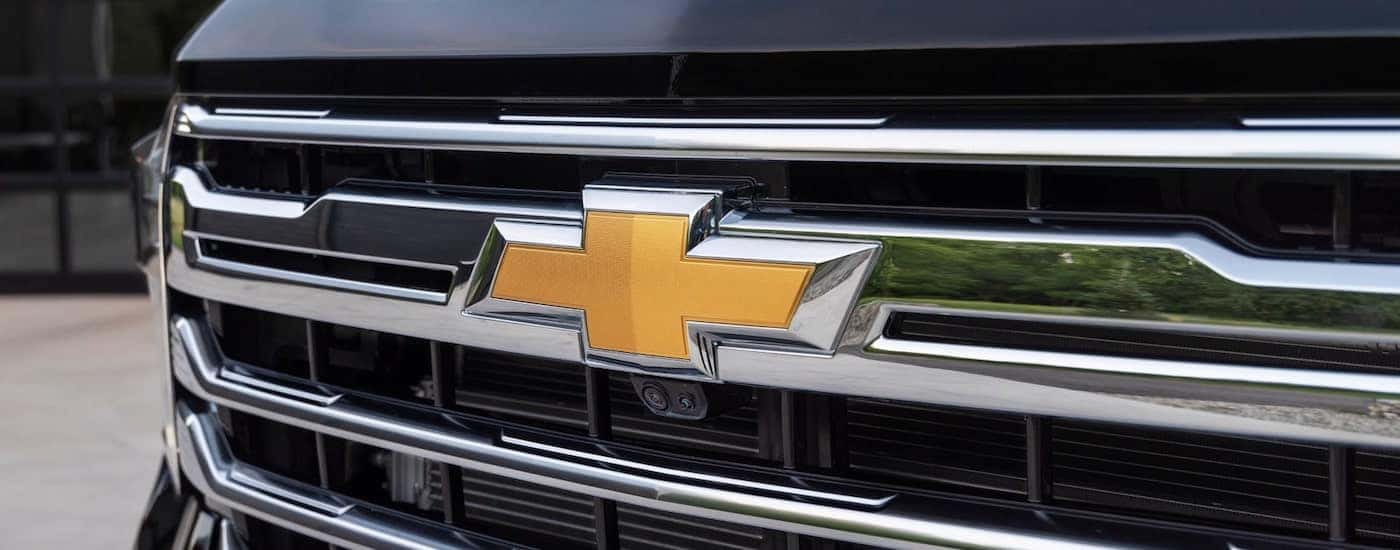 A close-up on the grille and badge of a black 2025 Chevy Silverado 2500 HD.