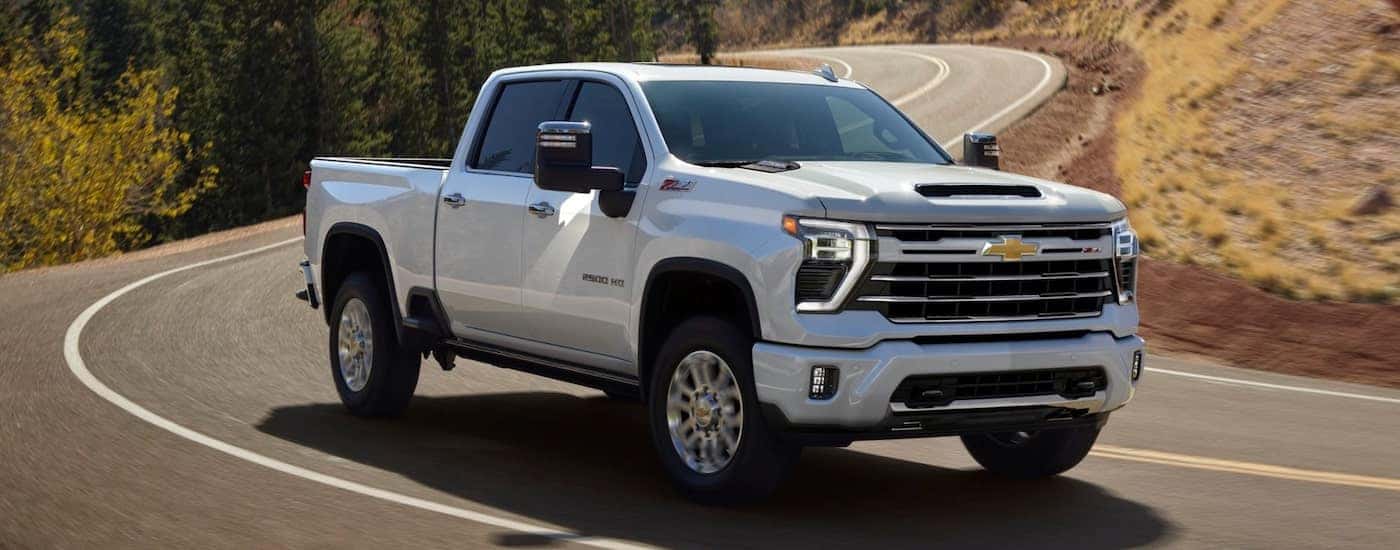 A white 2025 Chevy Silverado 2500 HD driving around a winding road.