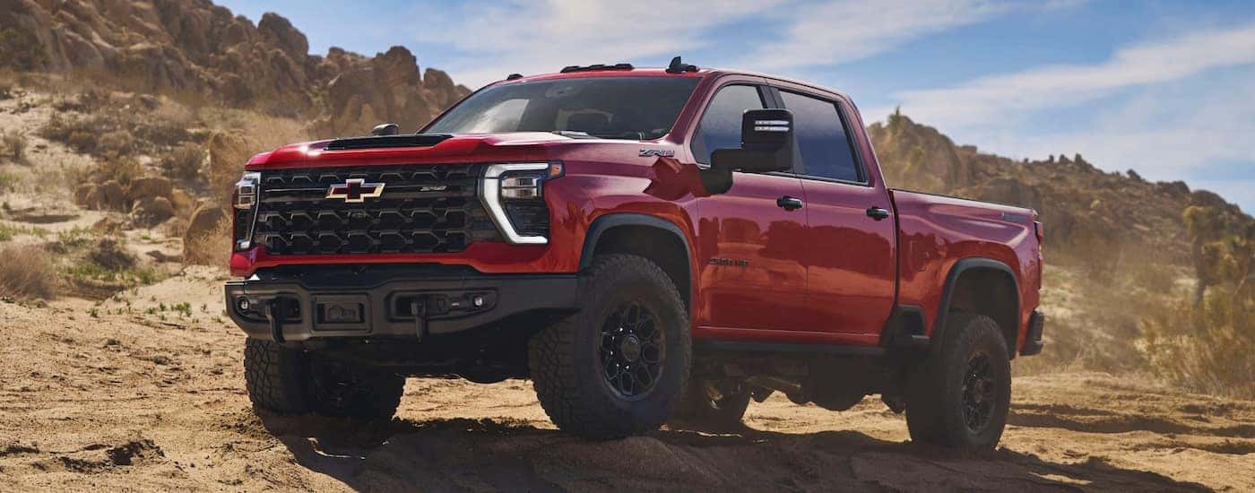 A red 2025 Chevy Silverado 2500 HD parked off-road and angled left.