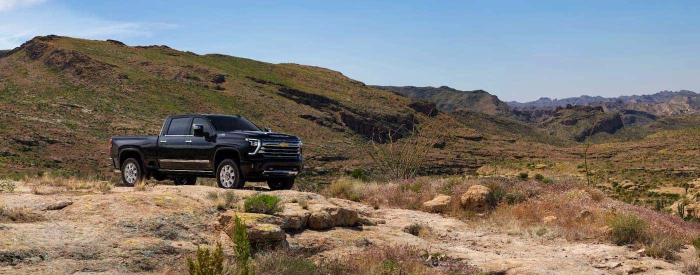 A black 2025 Chevy Silverado 2500 HD for sale in Charlotte parked off-road on a hill.