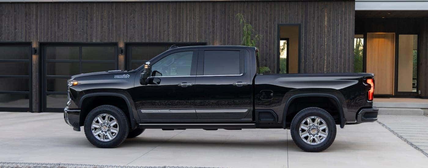 Side angle view of a black 2025 Chevy Silverado 2500 HD High Country parked outside a building.