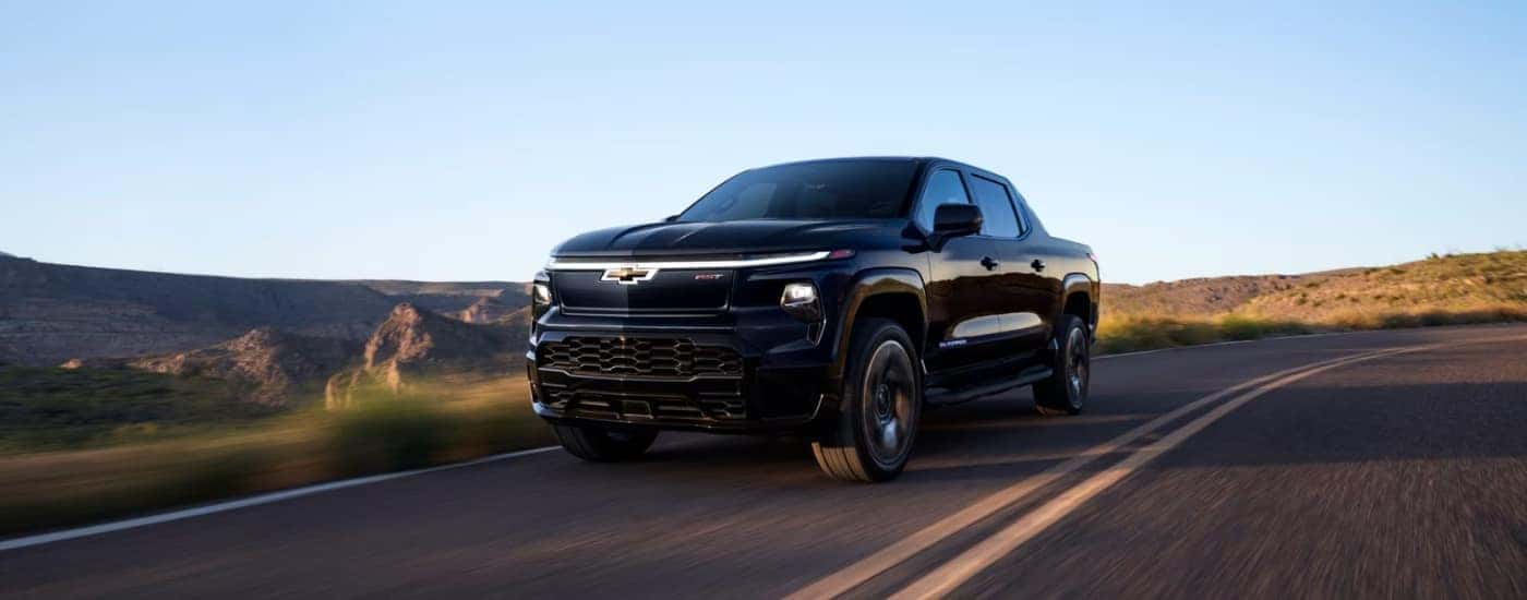 A black Chevy Silverado EV for sale near Mount Holly driving on an open road.