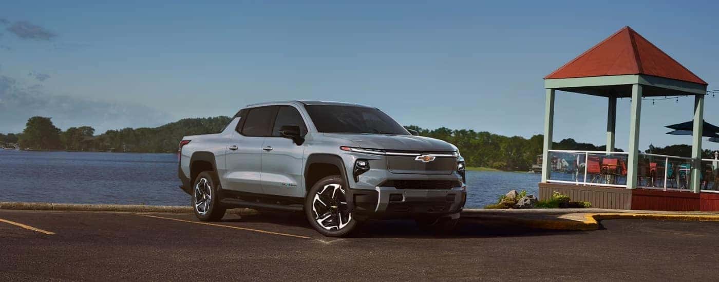 A light blue 2024 Chevy Silverado EV for sale in Charlotte parked near a lake.
