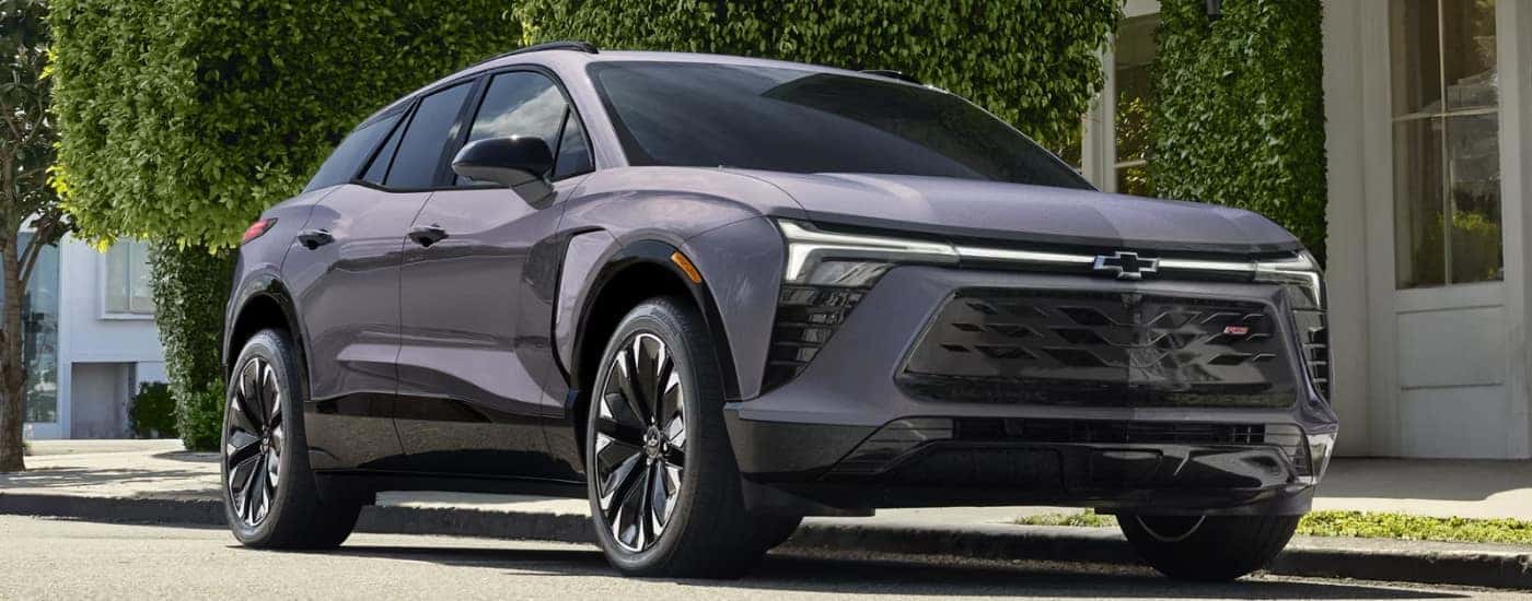 A grey 2024 Chevy Blazer EV for sale near Gastonia parked in front of a shop.