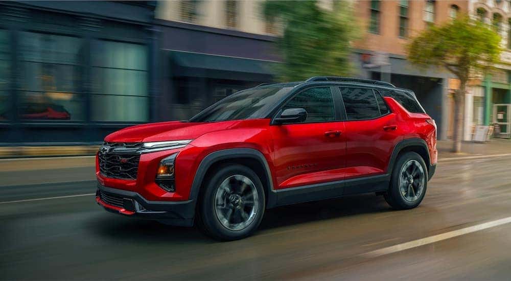 Red 2026 Chevy Equinox RS for sale driving down a city street.