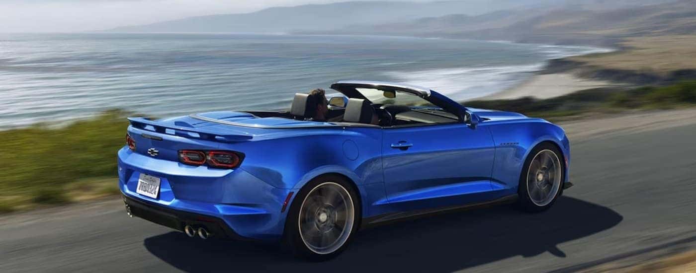 A blue 2024 Chevy Camaro driving near an ocean.