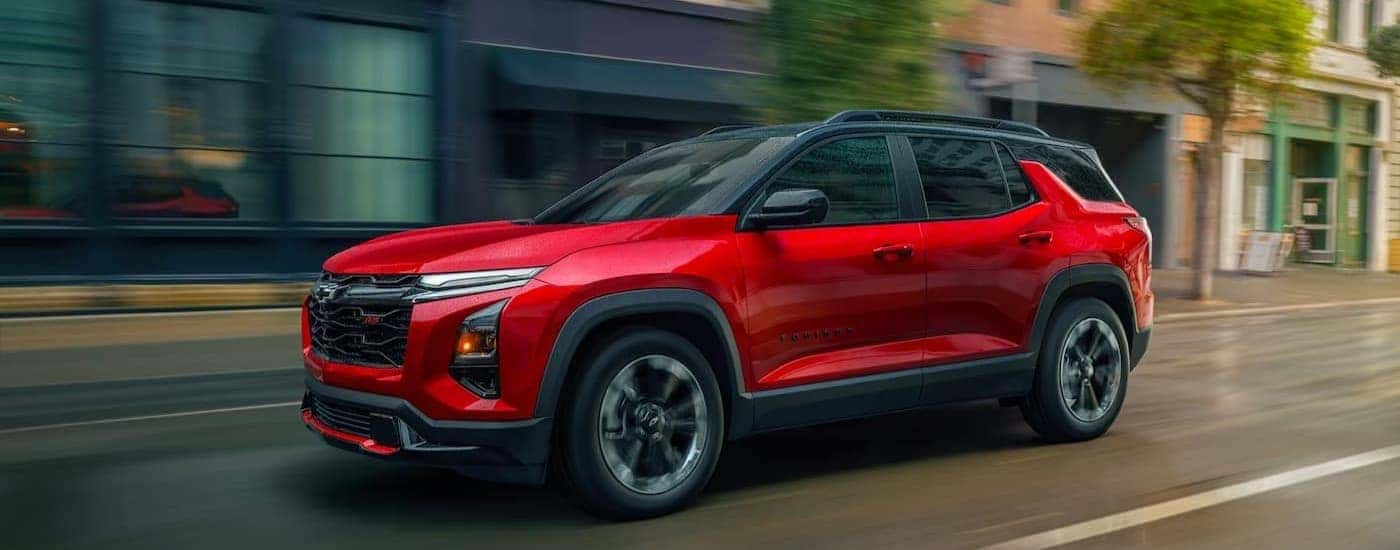 A red 2026 Chevy Equinox RS driving in a city.