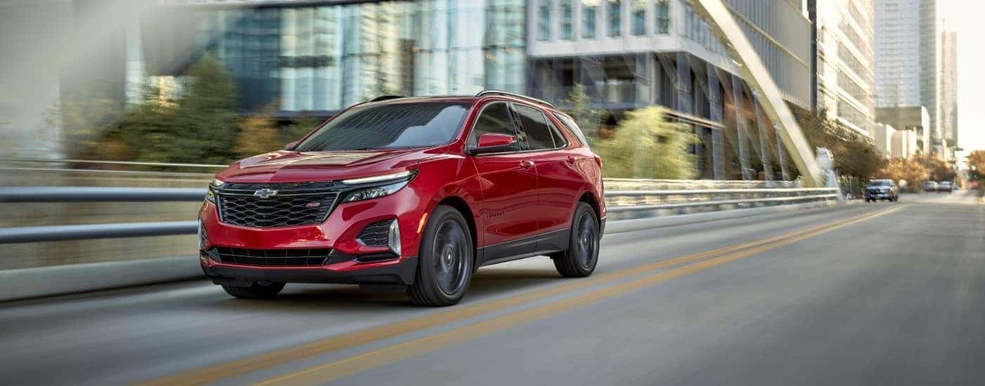 Red 2024 Chevy Equinox RS for sale near Kannapolis driving down a bridge.