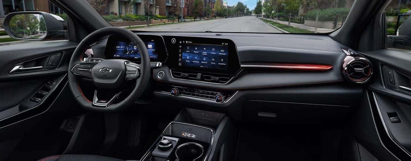 Steering wheel and infotainment screen in the black interior of a 2025 Chevy Equinox.