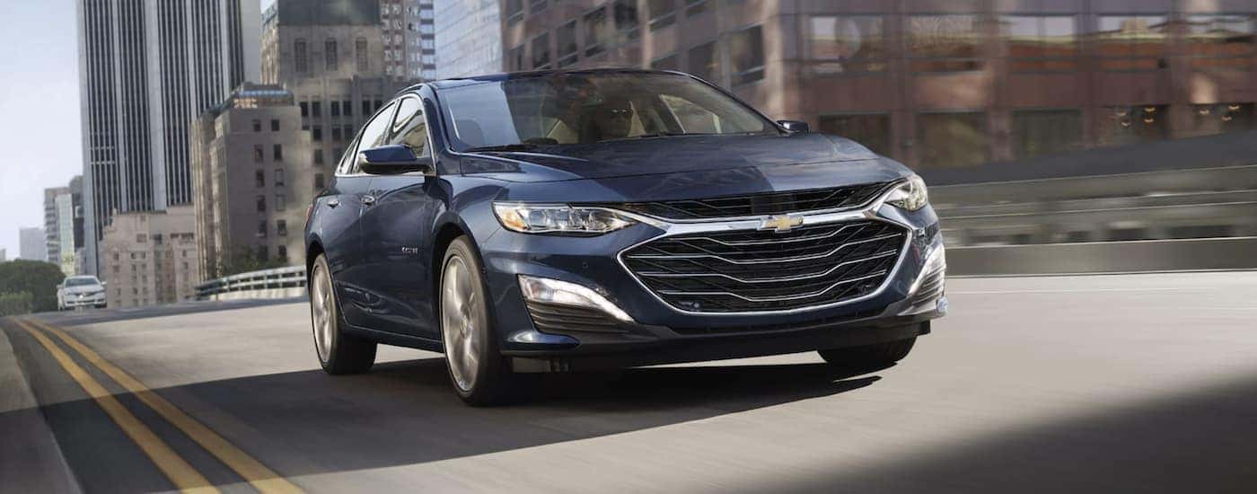 A blue 2022 Chevy Malibu driving in a city
