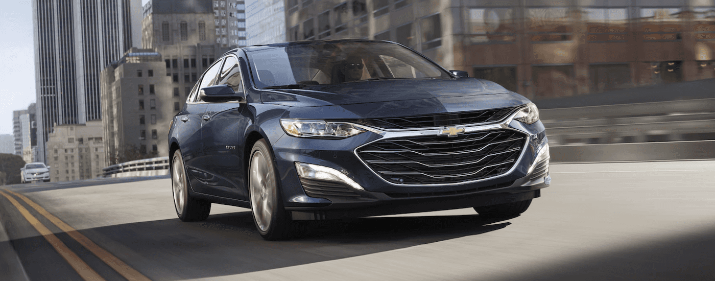 Blue 2022 Chevy Malibu driving down a road.