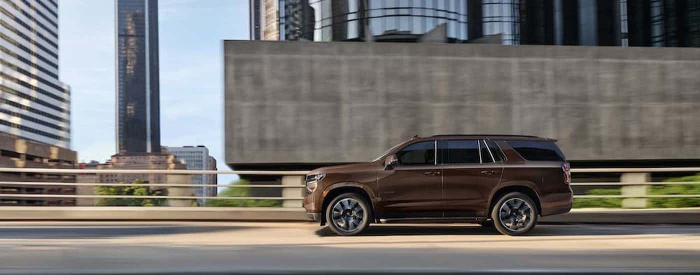 A brown 2022 Chevy Tahoe driving in a city.