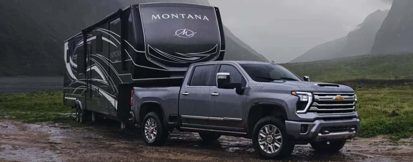 A gray 2024 Chevy Silverado 2500 HD towing a trailer.