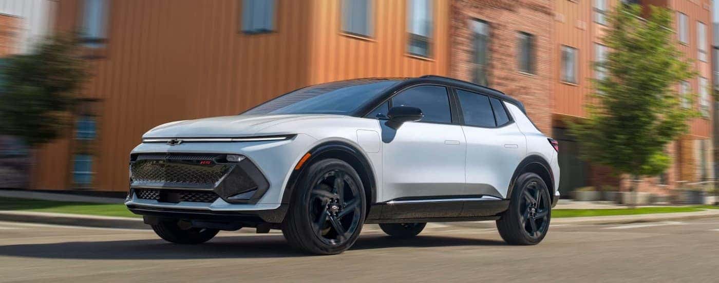 A white 2025 Chevy Equinox EV driving in a city.