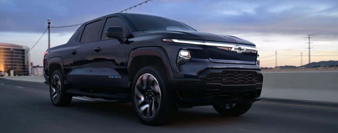 A blue 2025 Chevy Silverado EV RST driving to EVs for sale.