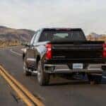 A black 2022 Chevy Silverado 1500 driving to view used cars for sale.