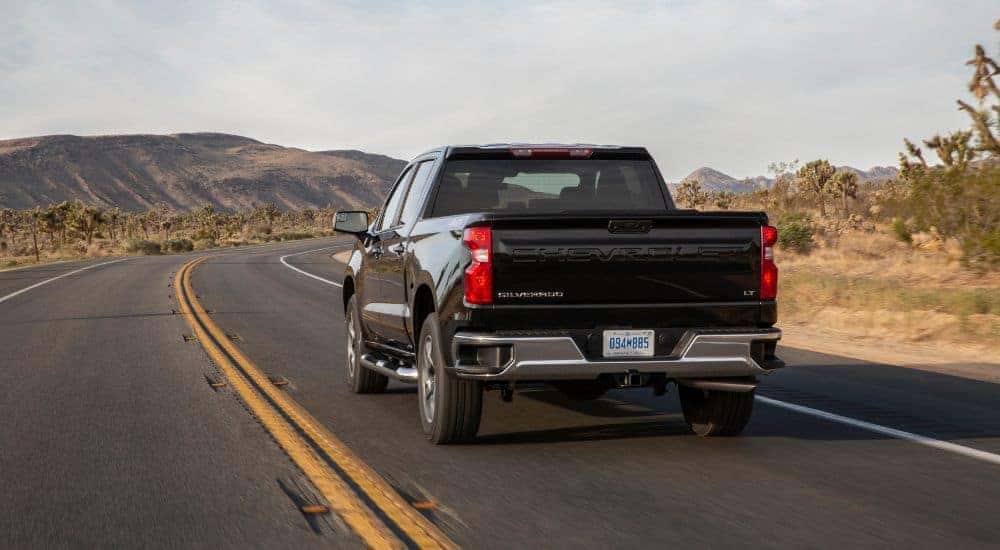 A black 2022 Chevy Silverado 1500 driving to view used cars for sale.