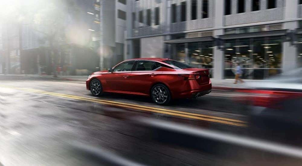 A red 2023 Nissan Altima driving in a city.