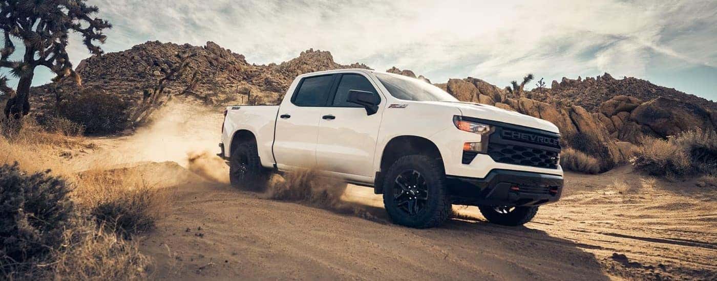 A white 2023 Chevy Silverado 1500 Z71 Trail Boss off-roading in sand