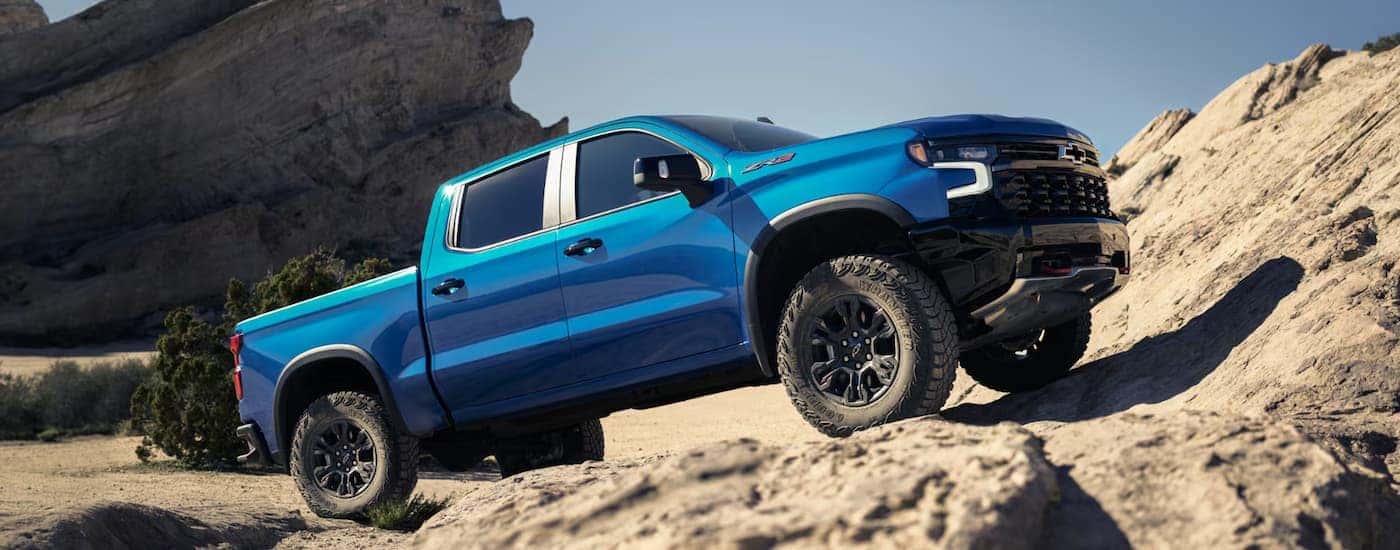 A blue 2026 Chevy Silverado 1500 off-roading on rocks