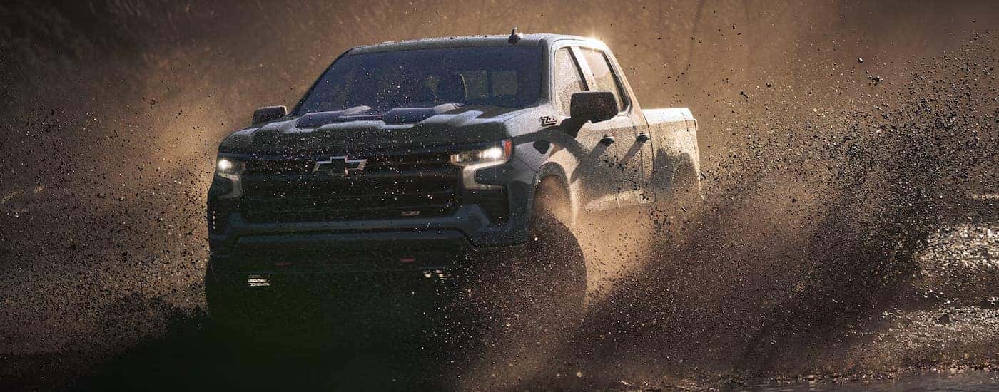 A blue 2026 Chevy Silverado 1500 off-roading in mud