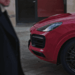 A person walking past a red 2021 Porsche Cayenne