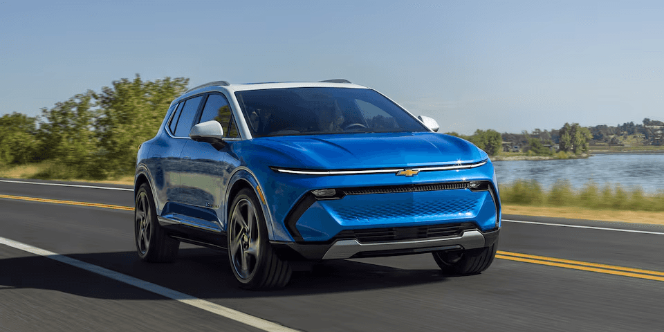 A blue Chevy Blazer EV driving along an empty highway road.
