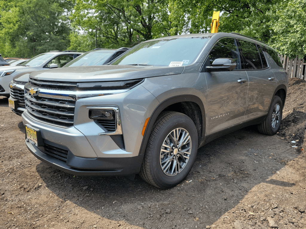 A silver 2025 Chevy Traverse parked in a parking lot. Three vehicles are seen beside it.