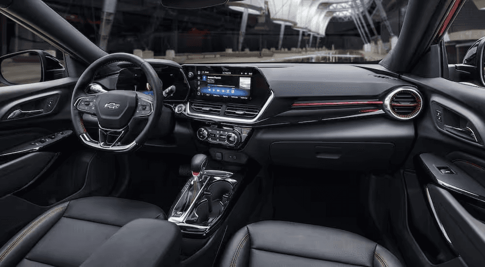 Interior view of the 2025 Chevy Trax featuring a modern dashboard, touchscreen infotainment system, and sporty red-accented trim.
