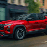 A red SUV drives down a wet city street, with buildings and motion blur in the background suggesting speed.