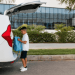 boy holding a bag behind a car