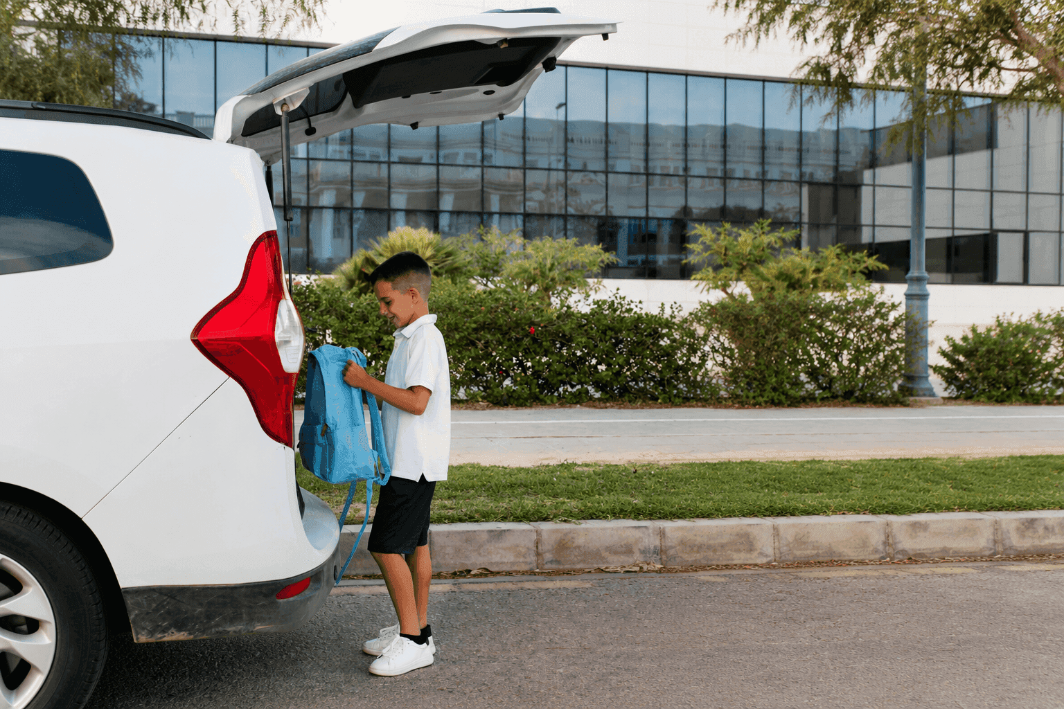 boy holding a bag behind a car