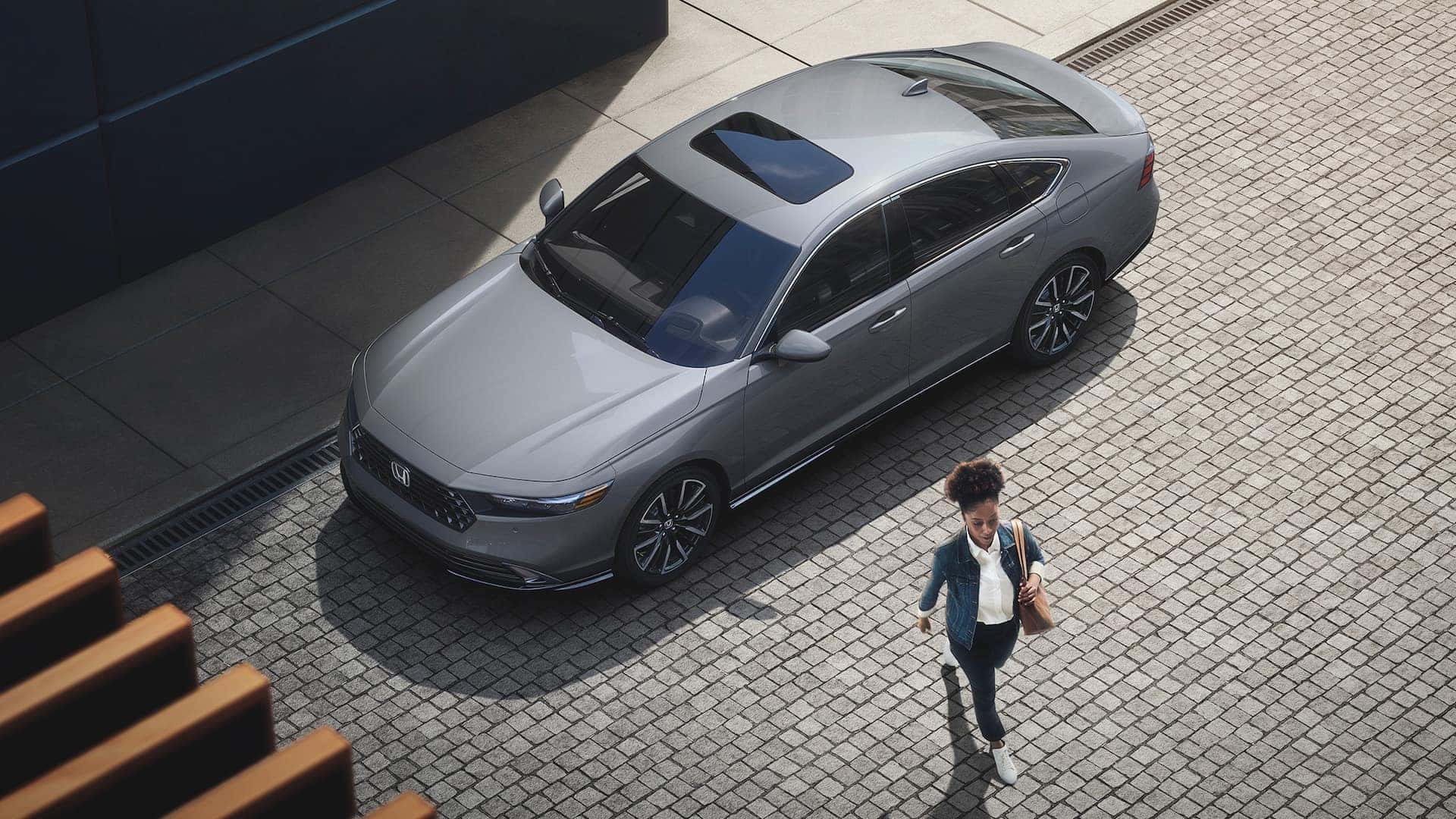 A grey 2025 Honda Accord, parked on the side of the street with a woman walking away from it