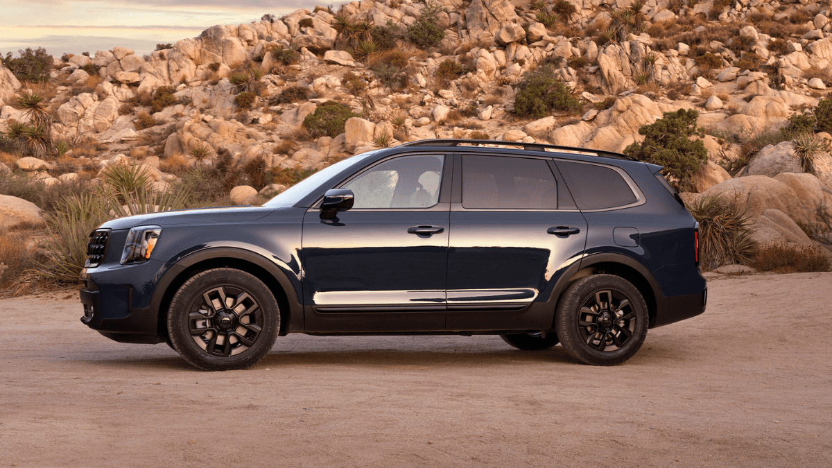 A blue Kia Telluride park next to a rocky outcrop