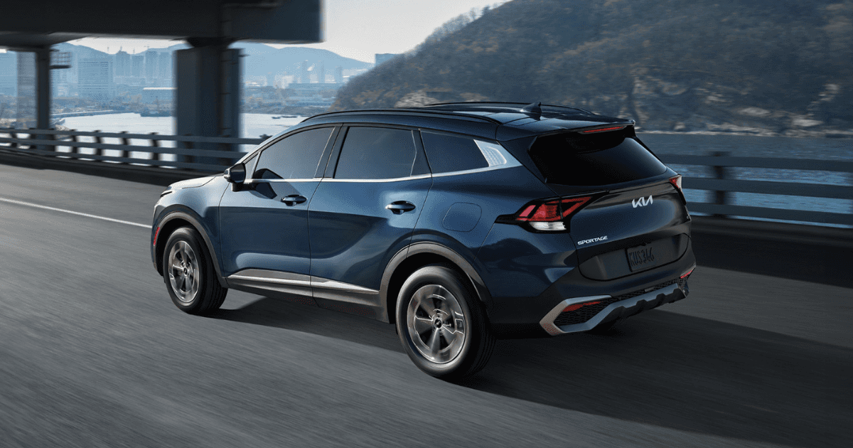 A blue 2025 Kia Sportage Hybrid driving across a bridge