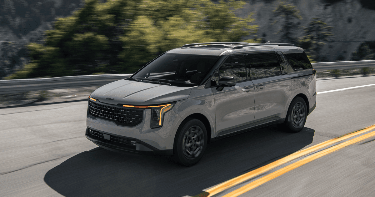A gray 2025 Kia Carnival Hybrid driving down the road